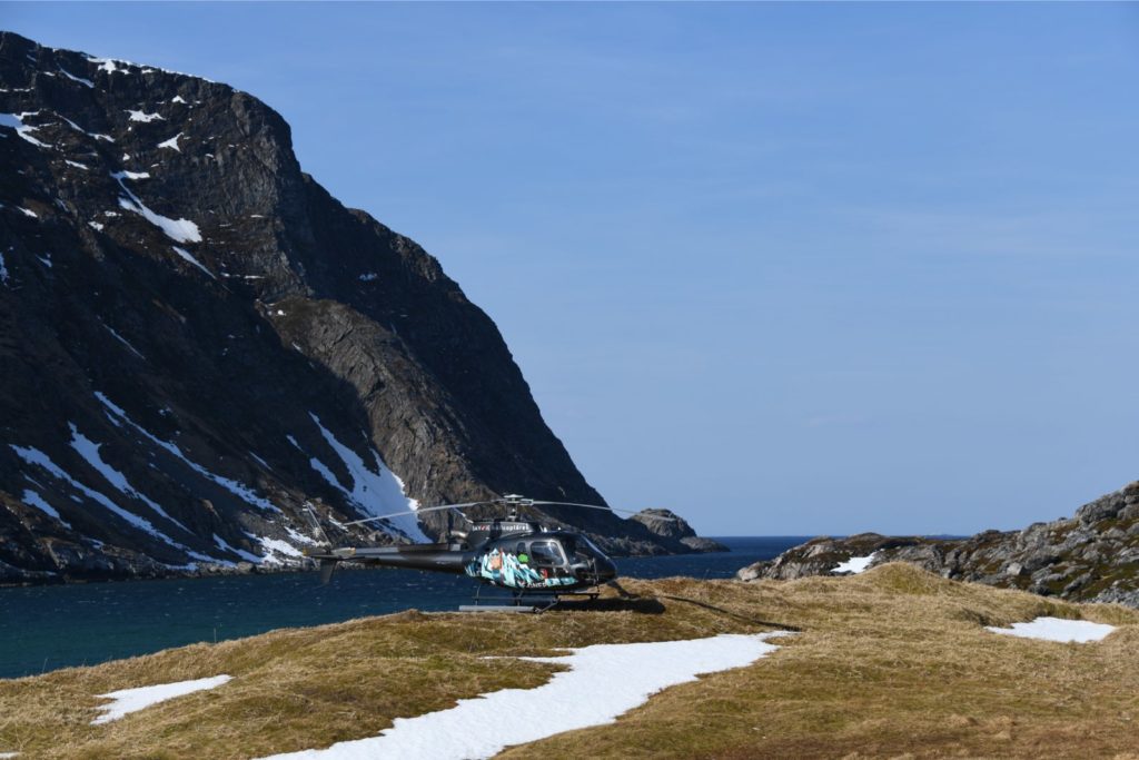 Helicopter on snowy mountain by the sea, showcasing Helipaddy landing locations.