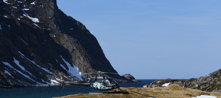 Helicopter on snowy mountain by the sea, showcasing Helipaddy landing locations.