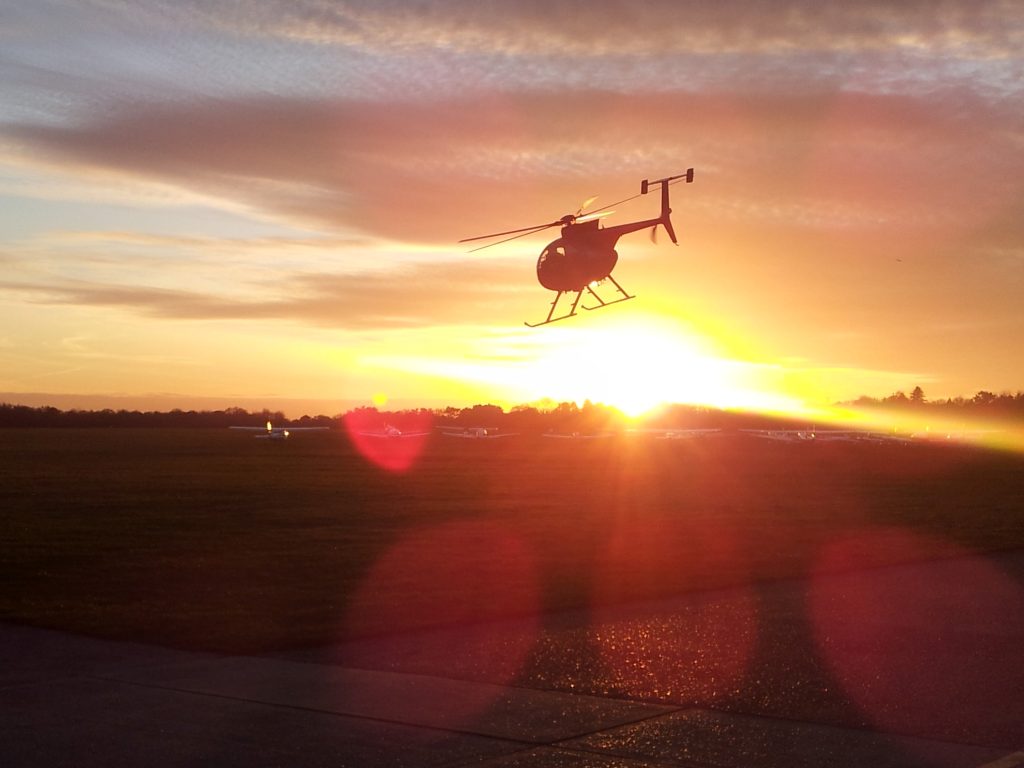 MD500 helicopter departing into the setting sun