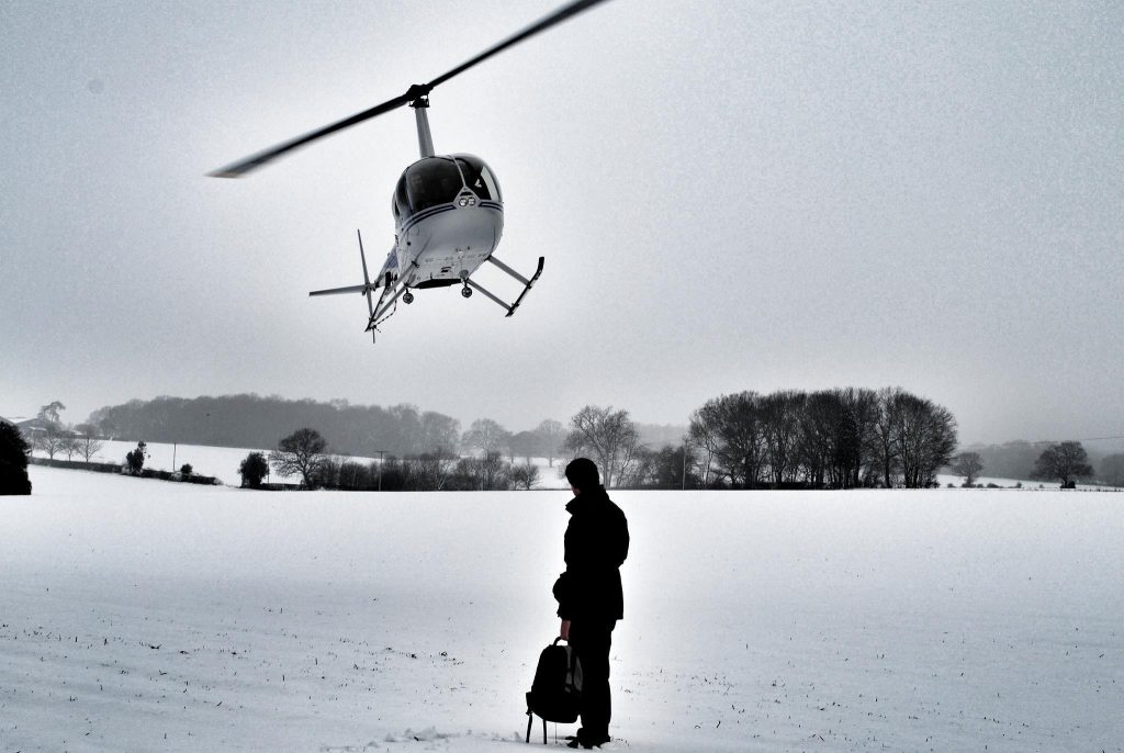Robinson R44 Helicopter landing in a snowy field