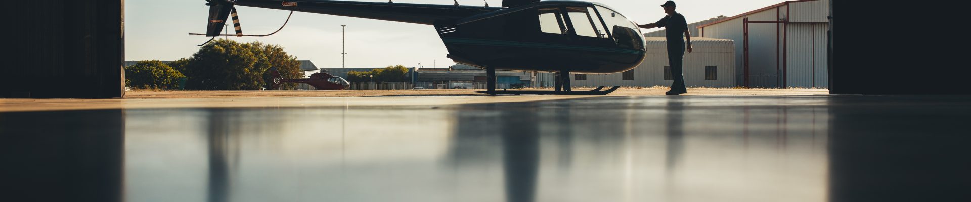 Silhouette of helicopter in the hangar with a pilot. Pilot doing preflight inspection of a helicopter.