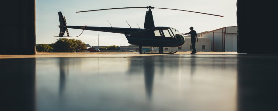 Silhouette of helicopter in the hangar with a pilot. Pilot doing preflight inspection of a helicopter.