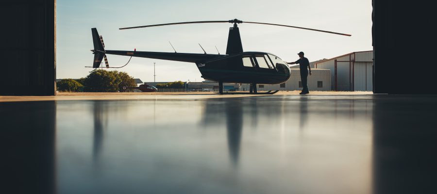 Silhouette of helicopter in the hangar with a pilot. Pilot doing preflight inspection of a helicopter.