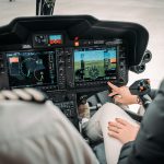 Helicopter cockpit with pilots using advanced controls, showcasing Helipaddy navigation system in flight.
