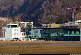 Modern airport terminal with control tower, mountain backdrop; discover landing spots with Helipaddy.