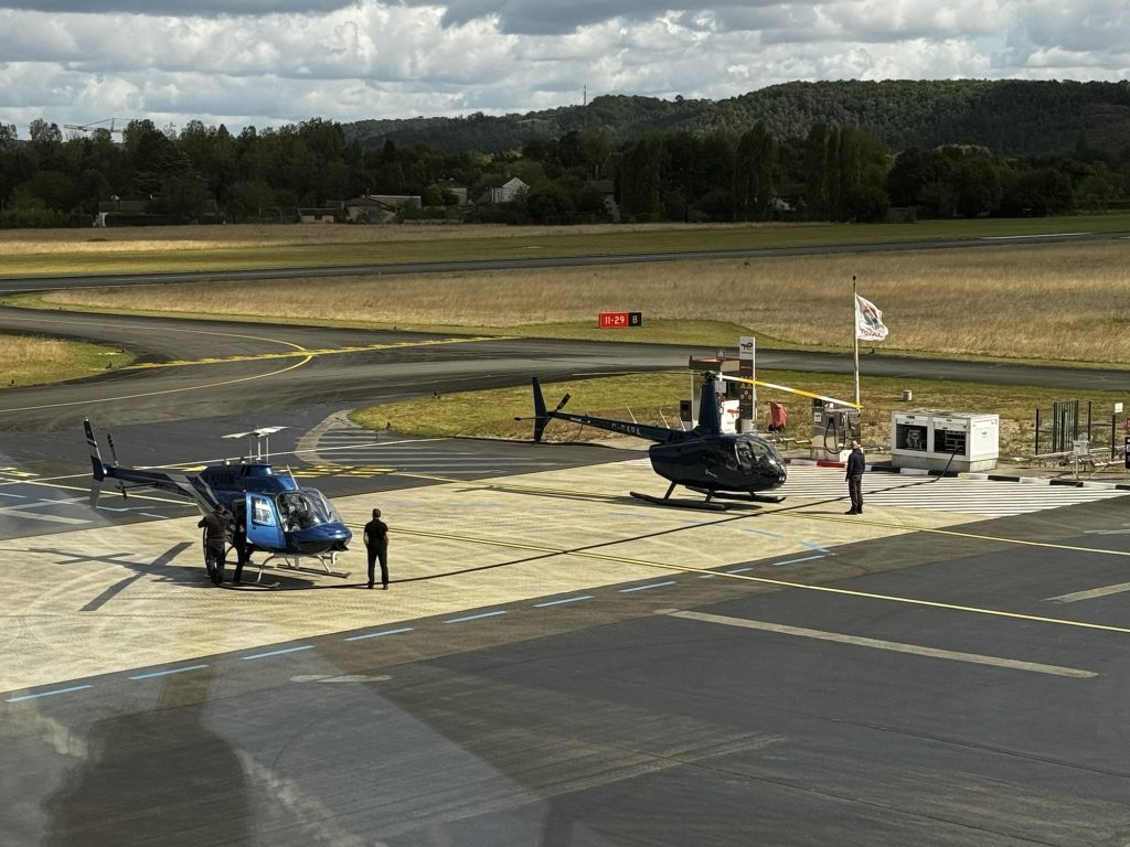 Two helicopters parked on an airfield with people nearby, highlighting Helipaddy landing locations.