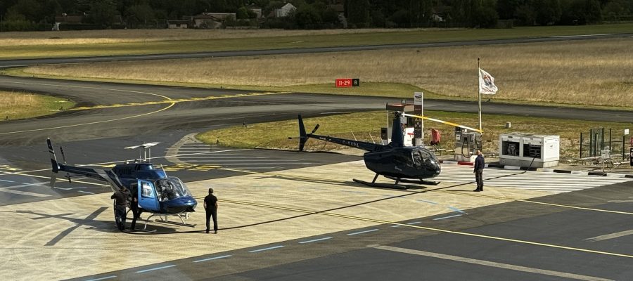 Two helicopters parked on an airfield with people nearby, highlighting Helipaddy landing locations.