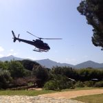 Helicopter landing on a scenic Helipaddy location with mountains and trees in the background.