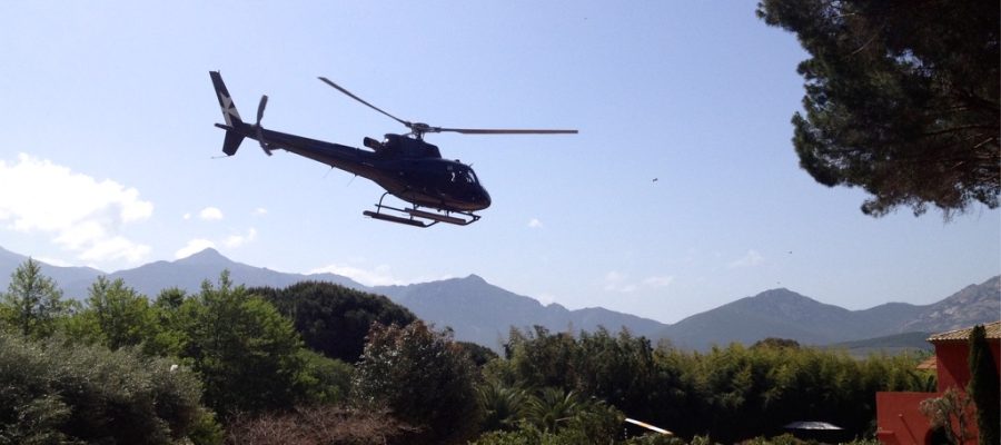 Helicopter landing on a scenic Helipaddy location with mountains and trees in the background.