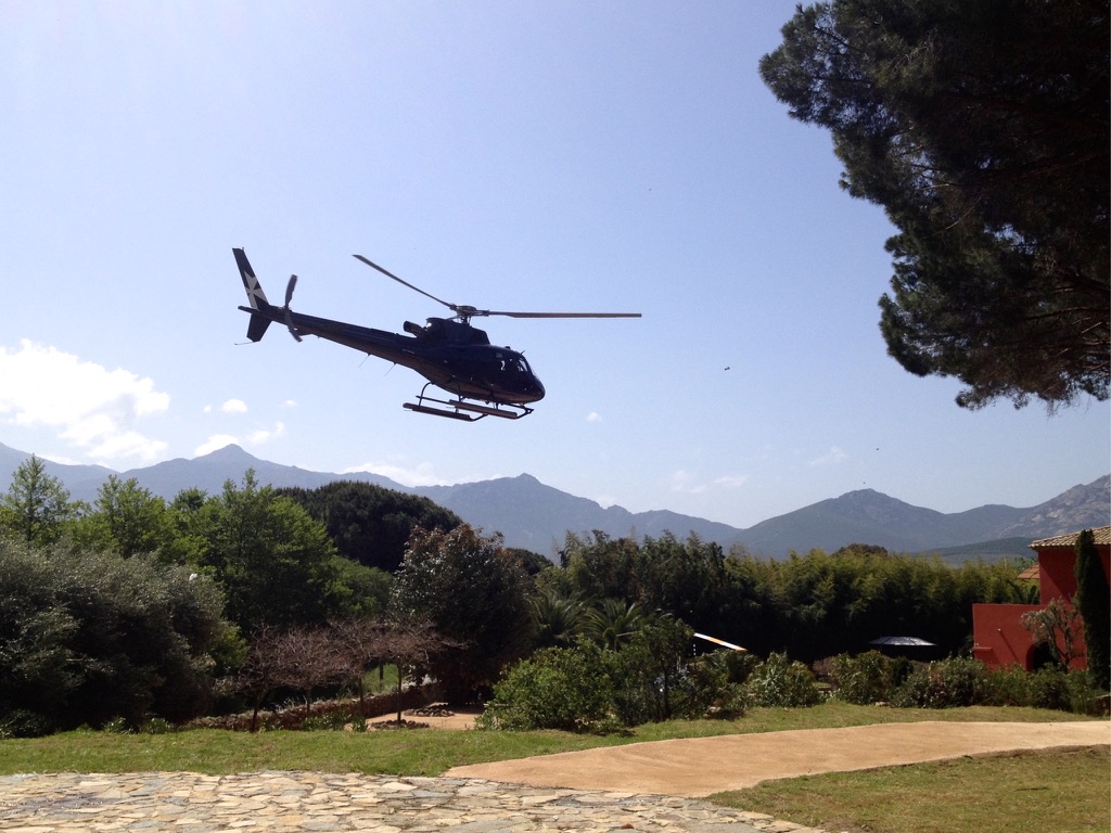 Helicopter landing on a scenic Helipaddy location with mountains and trees in the background.