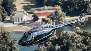 Helicopter flying above lush estate near historic building, featured on Helipaddy for scenic aerial adventures.
