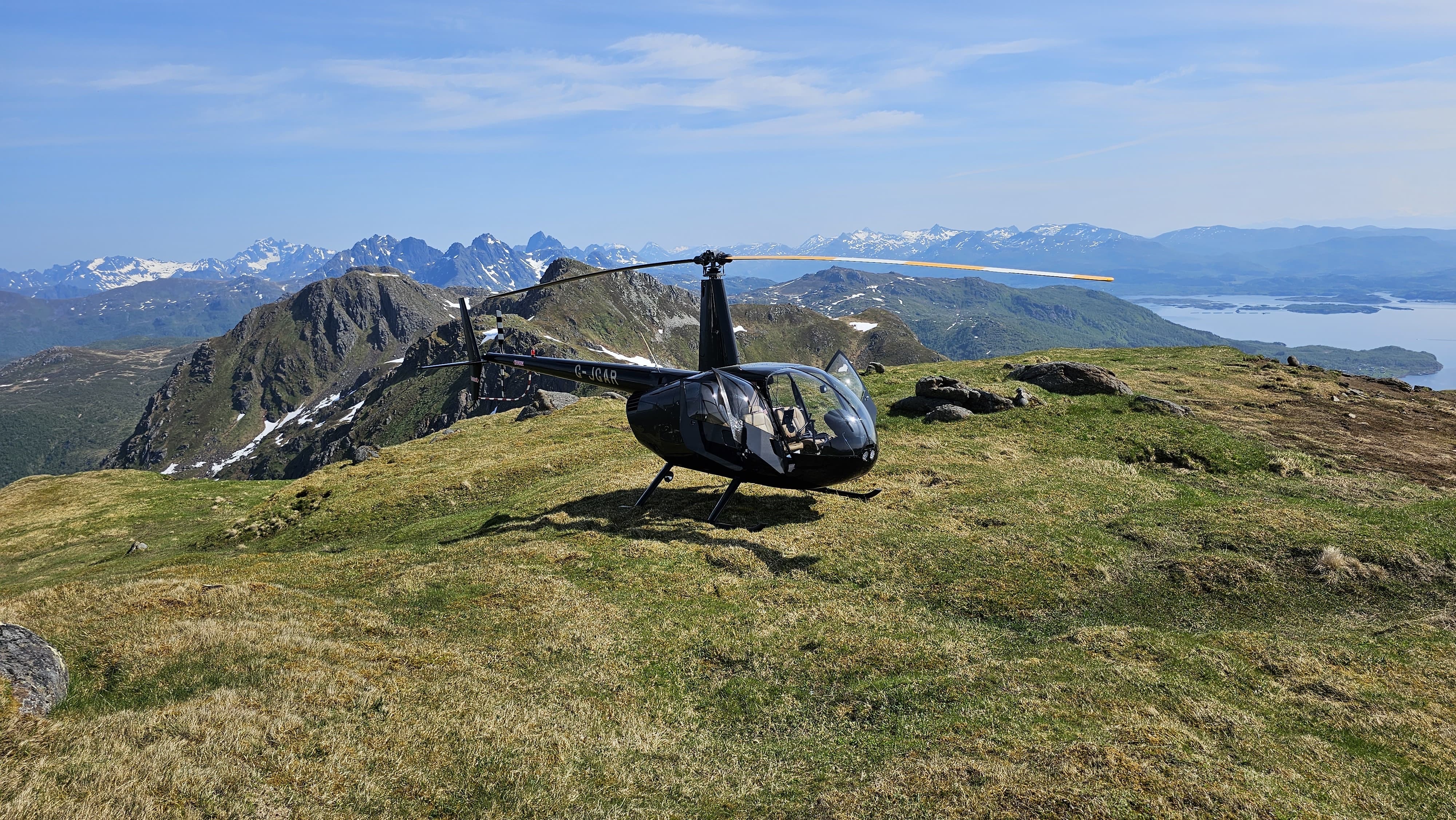 Helicopter on scenic mountain landing site with Helipaddy. Stunning aerial views of peaks and valleys.